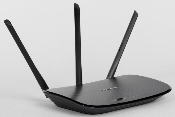 Black TP-Link wireless router with three external antennas on a white background.